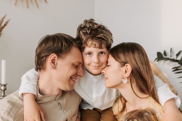 A joyful family moment with parents and their son embracing indoors.